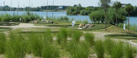 A golf course with bunkers, flags, and a lake in the background.
