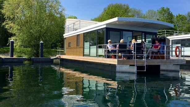 Un barco moderno con zona de comedor cubierta y cerramiento de vidrio.