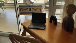 A laptop on a wooden table with a view of the beach and chairs outside. - Beautiful oceanfront villa with beach and great house reef (Hato)