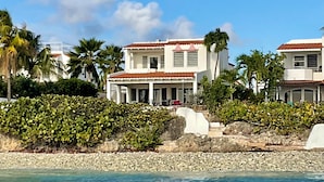 A beachfront property with a two-story building, a covered patio, and a rocky shoreline. - Beautiful oceanfront villa with beach and great house reef (Hato)