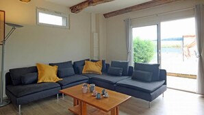 A modern living room with a sectional sofa, a wooden coffee table, and large windows offering a view of the outdoors. - Detached house in the countryside adapted for disabled people Pets welcome (Osmoy-Saint-Valery)