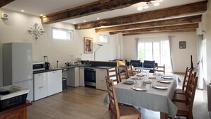 A spacious kitchen with wooden beams, a dining area with a table set for four, and a large window providing natural light. - Detached house in the countryside adapted for disabled people Pets welcome (Osmoy-Saint-Valery)