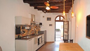 Una cucina con soffitto in legno, forno integrato e zona pranzo con tavolo e sedie in legno.