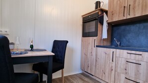 Een compacte keuken met houten kastjes, een magnetron en een eethoek met een tafel en stoelen.