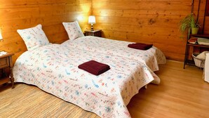 A cozy room with wooden walls, a bed with floral bedding, a nightstand with a lamp, and a small plant. - La Cure de Vernamiège (Mont-Noble)