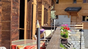 A wooden building with a balcony, outdoor seating, and flower arrangements. - La Cure de Vernamiège (Mont-Noble)