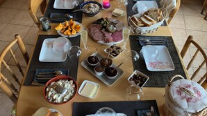 A wooden dining table set with various food items, including bread, cheese, and fruits, in a room with wooden walls and a window. - La Cure de Vernamiège (Mont-Noble)