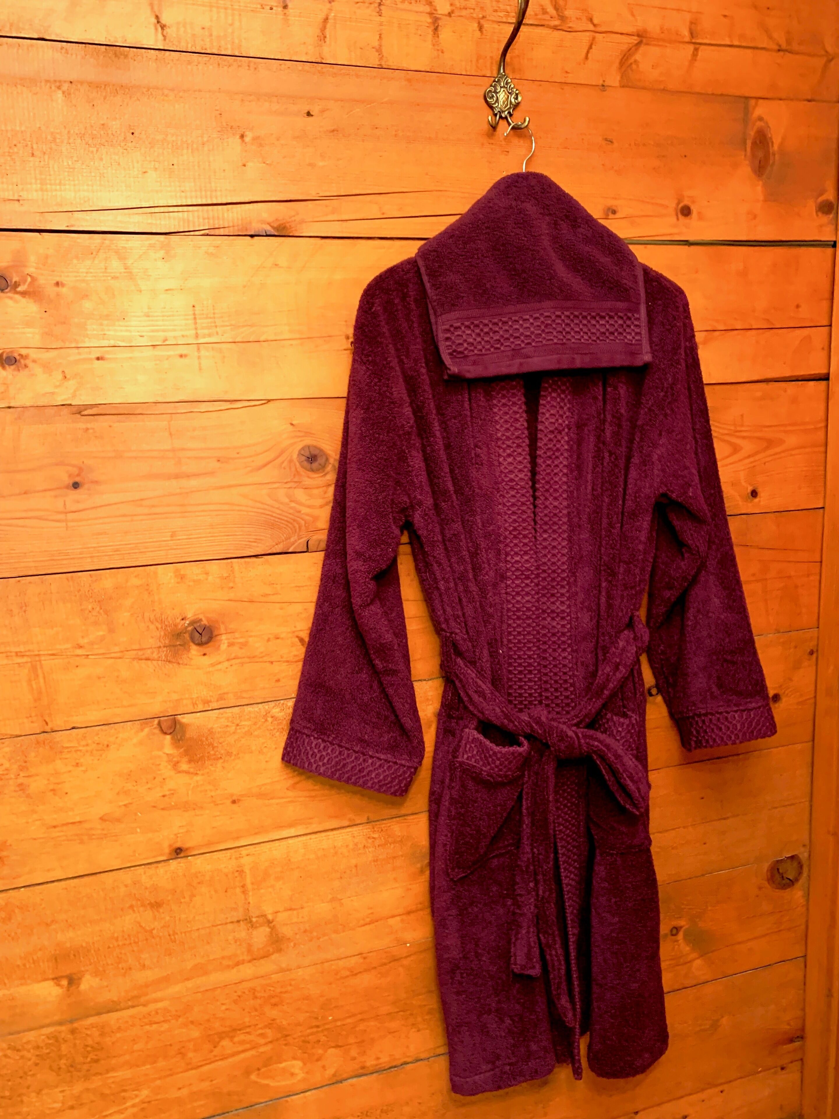 Une robe violette est suspendue à un mur en bois.