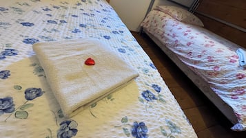 A bed with floral bedding, a red heart-shaped object, and a window with daylight.