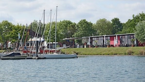 Ein Yachthafen mit mehreren Segelbooten, ein Restaurant mit Außenbestuhlung und ein Gebäude mit roter Fassade.