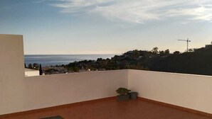 A terrace with two white plastic chairs and a table, overlooking a coastal view with a clear sky. - Stunning Central Penthouse with Breathtaking Sea and Mountain Views (Benalmádena)