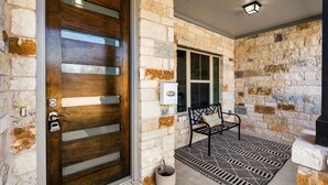 Une façade en pierre avec une porte en bois, un banc et un paillasson.
