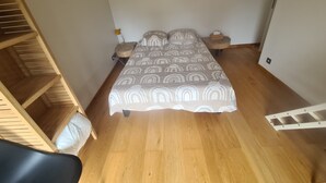 A bedroom with a bed, wooden shelving, a bedside table, and a nightstand. - ATYPICAL HOUSE with swimming pool and spa in the countryside 15 minutes from Annecy (Annecy)