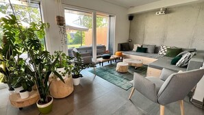 A modern living room with a grey sofa, a wooden coffee table, and a large potted plant. - ATYPICAL HOUSE with swimming pool and spa in the countryside 15 minutes from Annecy (Annecy)