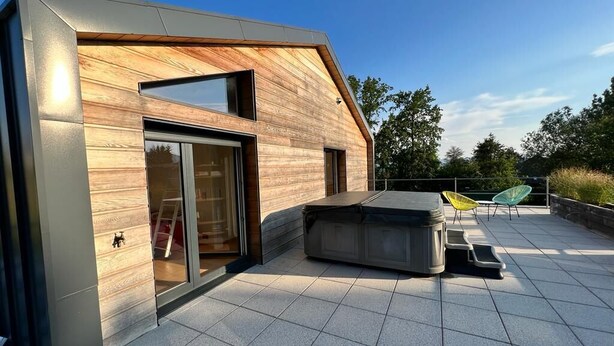 A modern house with a large glass door, a patio with outdoor furniture, and a sloped roof. - ATYPICAL HOUSE with swimming pool and spa in the countryside 15 minutes from Annecy (Annecy)