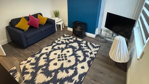 A living room with a dark blue sofa, patterned rug, and a fireplace. - 1br-2guests-freeparking-wifi-tv (Wigston)