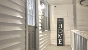 A clean, white exterior hallway with a welcome mat and a 'Welcome to Our Home' sign. - Medina Square Retreat - Spacious 4 bdrm home walking distance to the square (Medina)