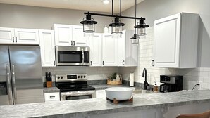 A modern kitchen with white cabinetry, stainless steel appliances, a marble countertop, and pendant lighting. - Medina Square Retreat - Spacious 4 bdrm home walking distance to the square (Medina)