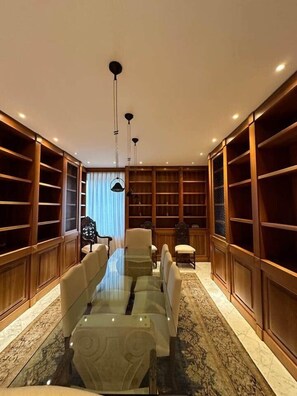 A spacious room with a long table, multiple chairs, and tall wooden bookshelves.
