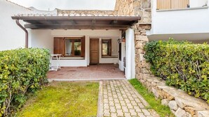 Ein Innenhof mit Steinmauer, einer Pergola und einem kleinen Garten.