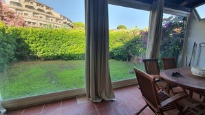 Ein Balkon mit Blick auf einen gepflegten Garten und ein Gebäude im Hintergrund.