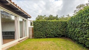 Ein modernes Haus mit Glastür, gepflegtem Rasen und dichter Hecke.