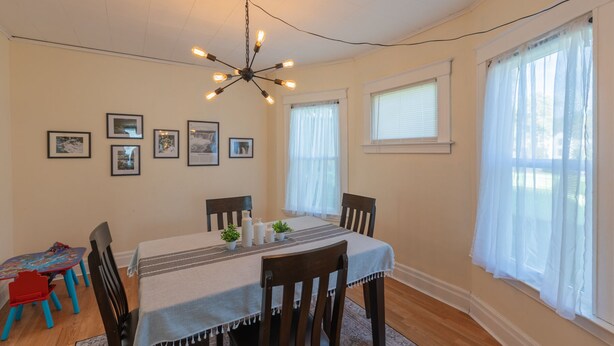 A dining room with a table set for four, surrounded by chairs, a chandelier, and framed pictures on the wall. - 10% Off • Spacious 3BR Retreat w/ Breakfast, AC & WiFi • 5 Min to Niagara Falls (Niagara Falls)
