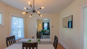 A dining area with a table set for four, a chandelier, and a view into a living room with a green sofa.