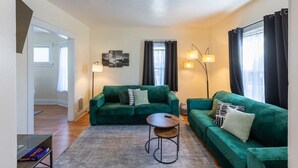A living room with two green sofas, a round coffee table, and a floor lamp. - 10% Off • Spacious 3BR Retreat w/ Breakfast, AC & WiFi • 5 Min to Niagara Falls (Niagara Falls)