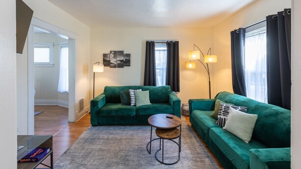 A living room with two green sofas, a round coffee table, and a floor lamp.