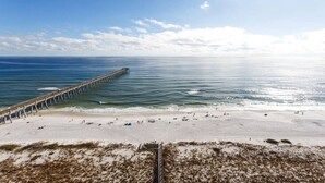 A beach with a long pier extending into the ocean, sandy beach, and clear skies. - Absolutely Shore, Navarre Beach (Navarre)