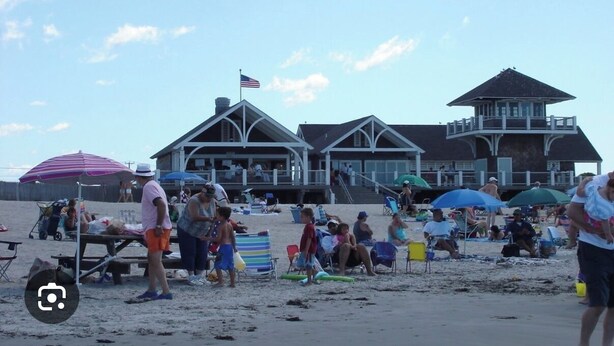 Une plage avec des maisons de plage, des parasols et des gens.