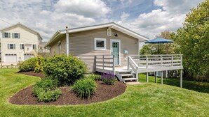 Une maison de plain-pied avec une terrasse à l’avant, une boîte aux lettres et une porte dotée d’une fenêtre.