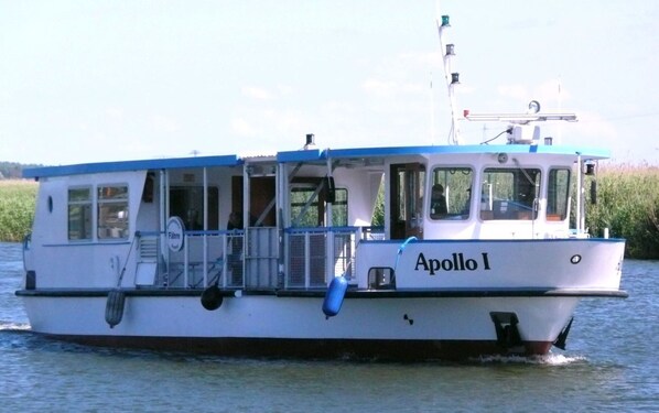 A boat named Apollo I with a cabin and a blue roof, floating on water.