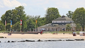 En byggnad med ett kupoltak, belägen nära en strand där det finns flaggor och människor.