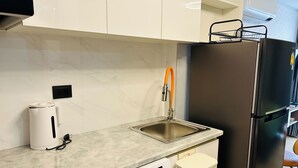 Eine moderne Küche mit integriertem Geschirrspüler, einer Edelstahl-Spüle und einem schwarzen Kühlschrank.