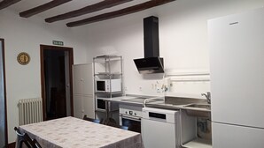 A compact kitchen with a built-in oven, microwave, and dishwasher. There is a dining table with chairs, a radiator, and a door marked "SALIDA". - HOME TO ENJOY IN STYLE !!!! Garden, barbecue, swimming pool, swings, ping-pong. (Arguedas)
