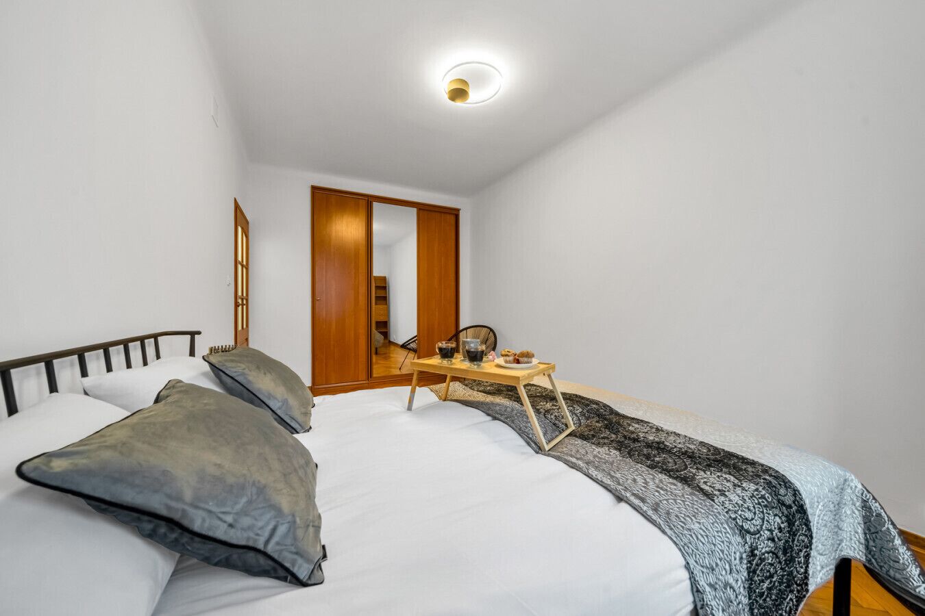 Een slaapkamer met een bed, nachtkastje en een klein tafeltje met ontbijtartikelen.
