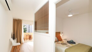 A hotel room with a bed, a ceiling fan, and a window with blinds.