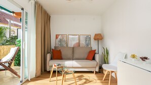 A modern living room with a sofa, coffee table, and a dining area.