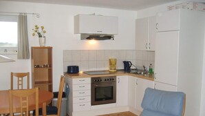 A compact kitchen with a dining table, chairs, a built-in oven, and a refrigerator. - Hausboot in Kroeslin am Bodden (Kröslin)