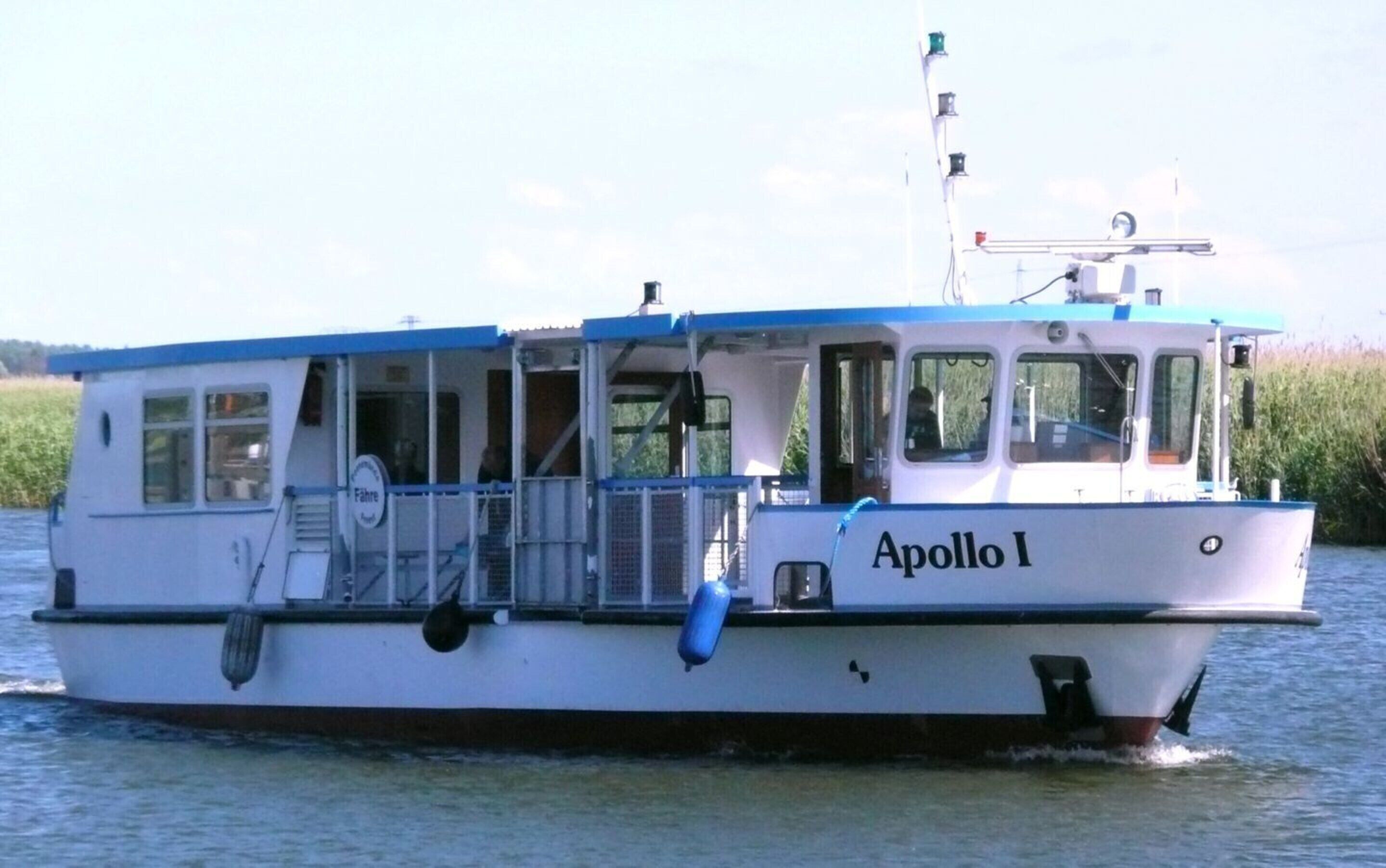 Un bote llamado Apollo I con camarote y techo azul, flotando sobre el agua.