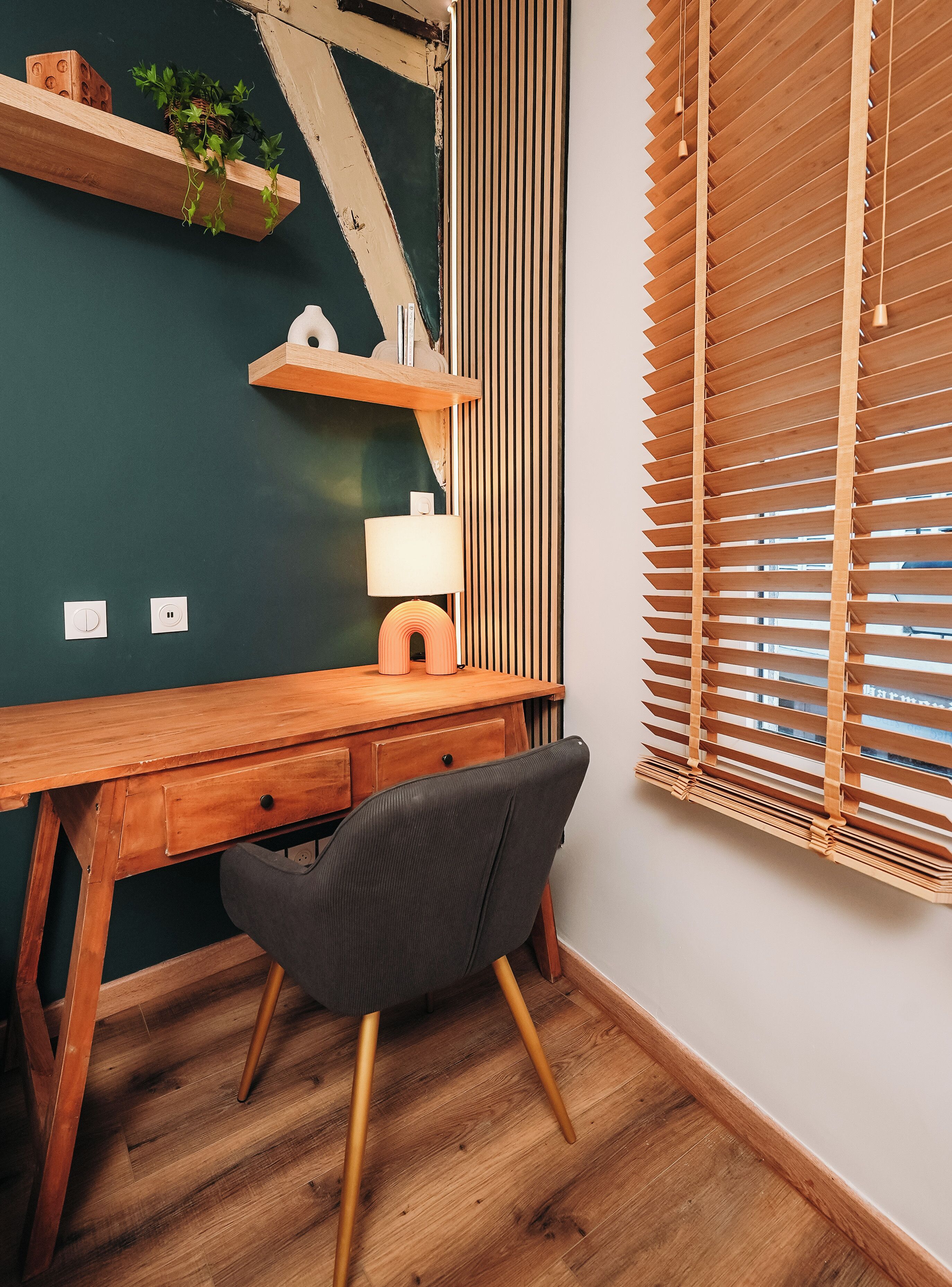 A wooden desk with a chair, a lamp, and a plant on a shelf.