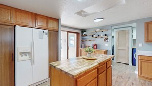 Une cuisine avec des meubles de rangement en bois, un réfrigérateur blanc, un plan de travail en bois et un four encastré.