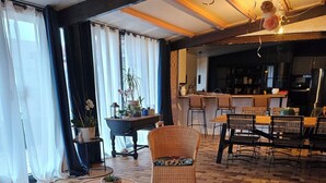A spacious living area with wicker furniture, a round table, and a kitchen in the background.