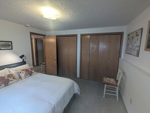 A bedroom with a bed, a chair, and two wardrobes.