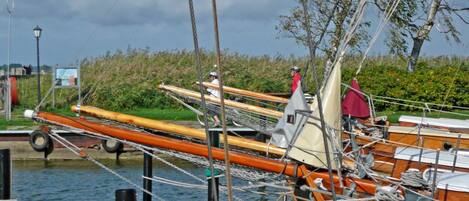 A row of boats docked at a marina with a grassy area and a lamppost in the background.