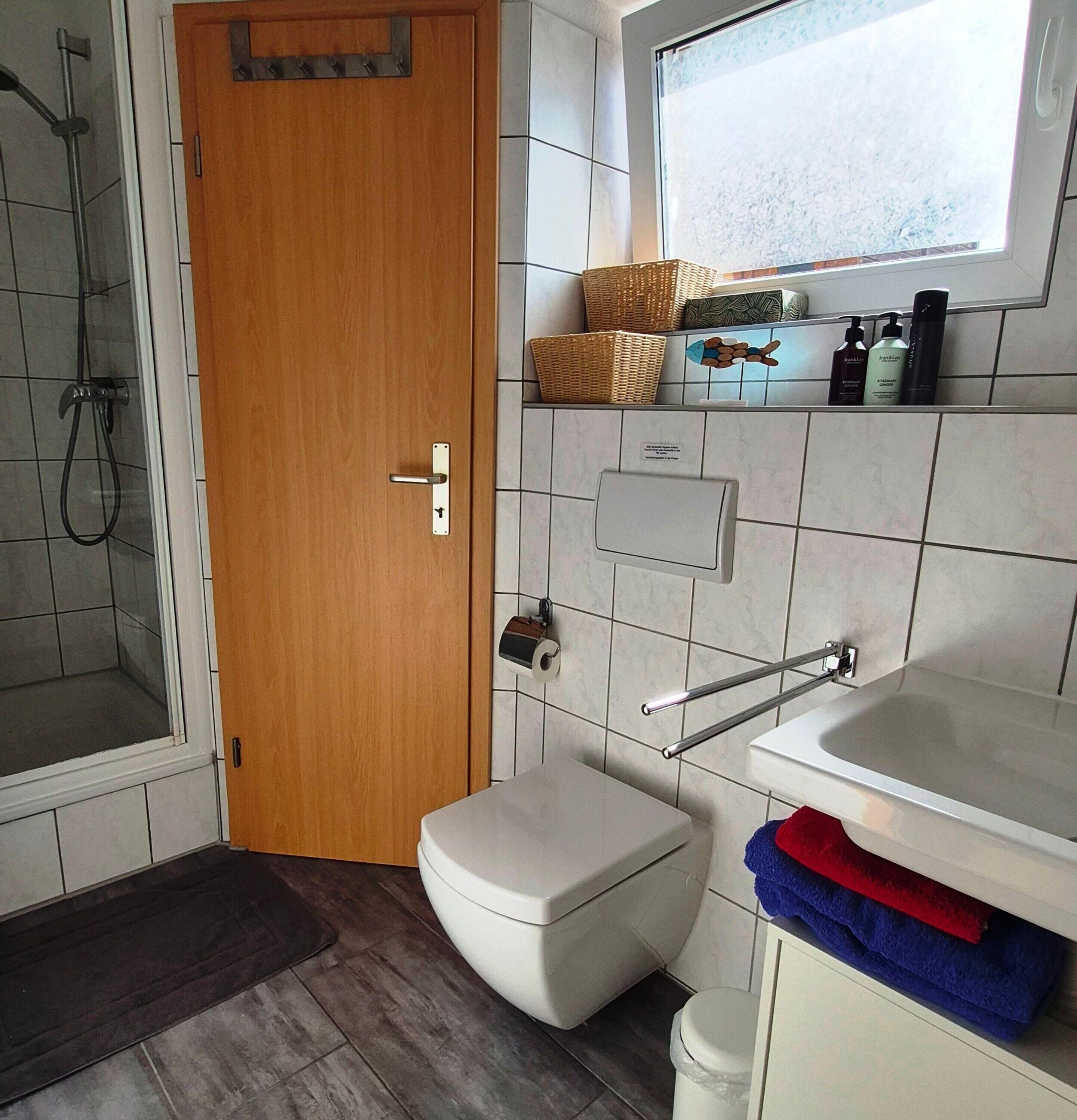 A bathroom with a shower, toilet, sink, and window.