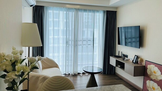 Une chambre d’hôtel avec un lit, une télévision, une petite table et une fenêtre avec des rideaux.