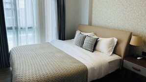 Une chambre d’hôtel avec un lit, une table de chevet avec une lampe et une fenêtre avec des rideaux.